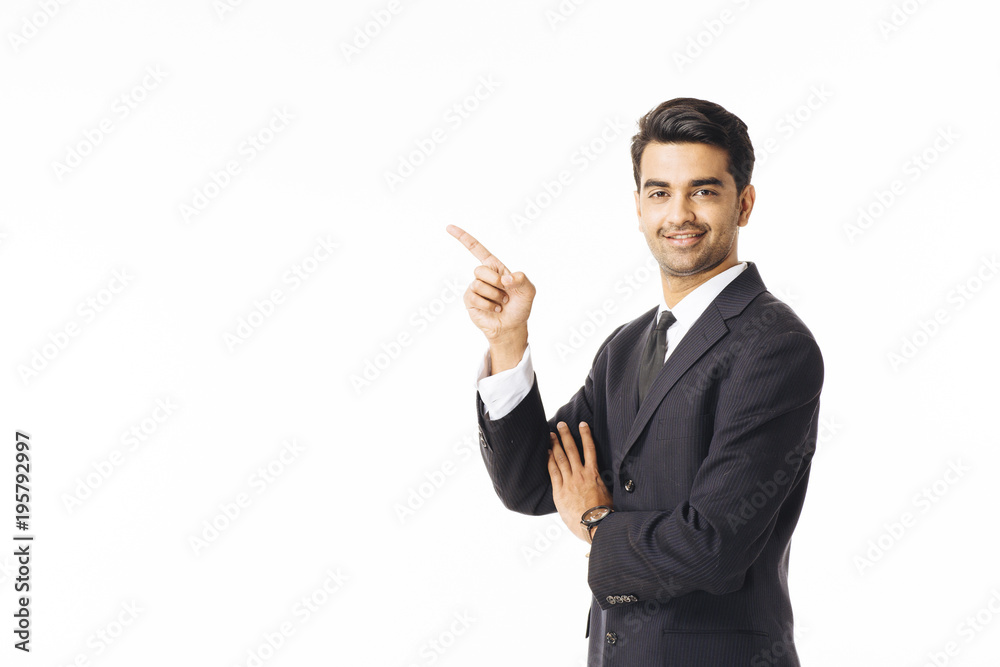Portrait of a smiling, successful businessman in black suit and tie pointing up isolated on white background