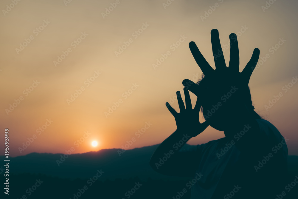 Silhouette young girl with her hand extended signaling to stop at the sunset time. Concept of human rights.