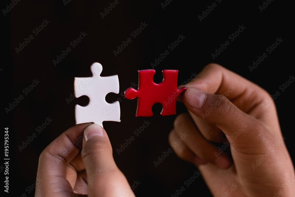 Hands trying to fit two puzzle pieces together Hands trying to fit two puzzle pieces together