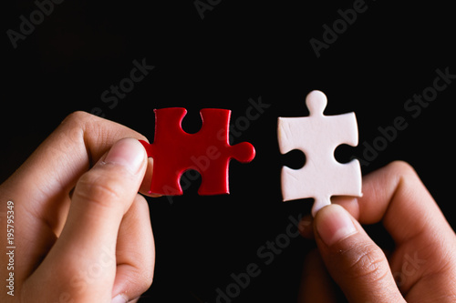 Hands trying to fit two puzzle pieces together