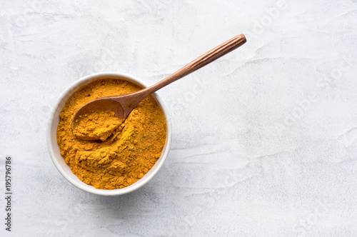 Golden turmeric powder and wooden spoon. Concrete background. Traditional indian spice. Top view. 
