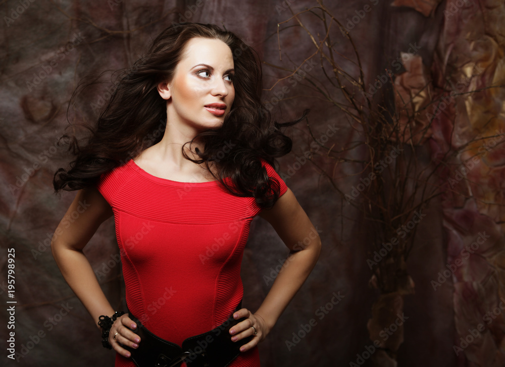 Beautiful brunette in a red dress posing on a theatrical backg Beautiful brunette in a red dress posing on a theatrical backg
