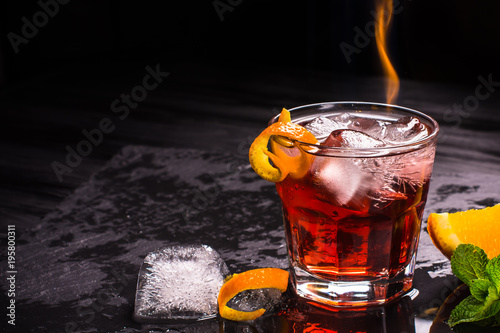 Mezcal Negroni cocktail with flames. Smoky Italian aperitivo. Orange peel. photo