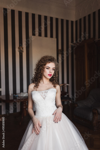 portrait of a curly bride who is standing in a room