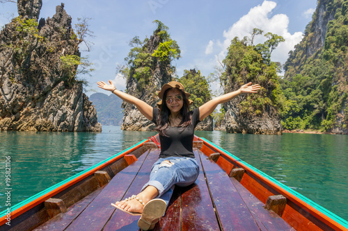 asian young woman traveling by wooden boat at sunrise among the island Khao Sok National Park, Thailand © suriya