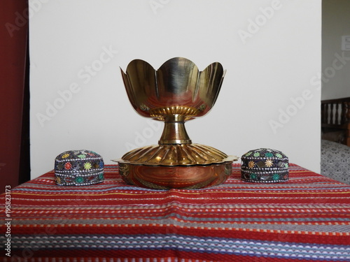 bronze bowl on red mat, Indian tradition, turmeric and kumkum holder, flower bowl, decoration photo