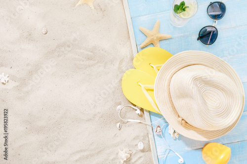 Travel vacation concept. Traveler accessories on sand. Straw hat, sunglasses, flip flops, cocktail, sunblock with copy space. Summer background