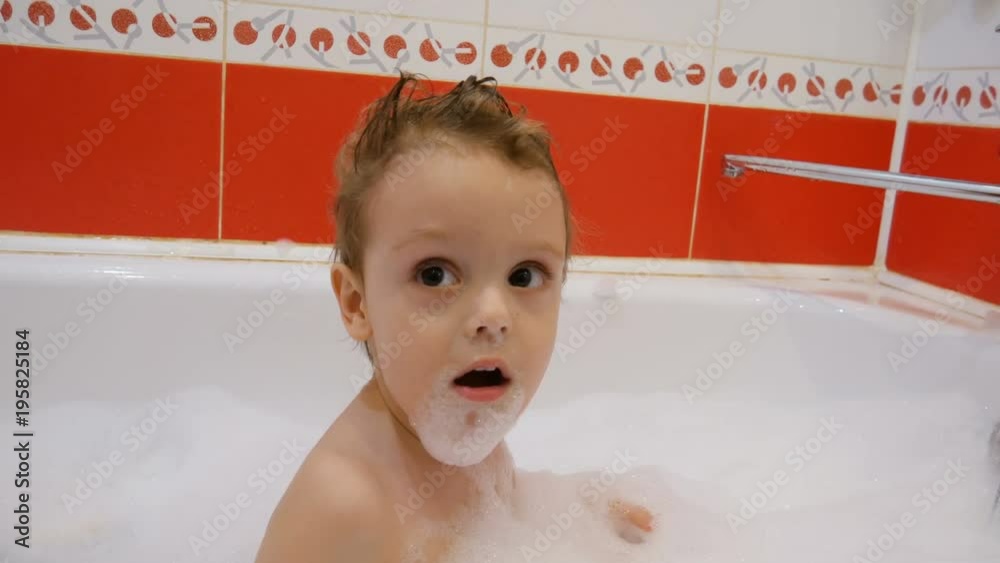 A baby smiles and laughs while playing with a toy in a bubble bath A baby smiles and laughs while playing with a toy in a bubble bath