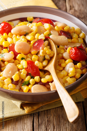 Traditional succotash of corn, butter beans, tomatoes and bacon close up in a bowl. vertical