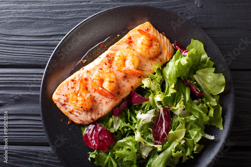 Delicious food: baked salmon with prawns in honey sauce and fresh salad on a plate close-up. horizontal top view