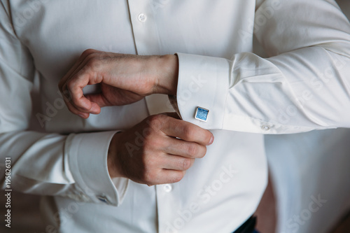 Groom hands hold cufflinks. Elegant gentleman clother, white shirt and black belt © romannoru