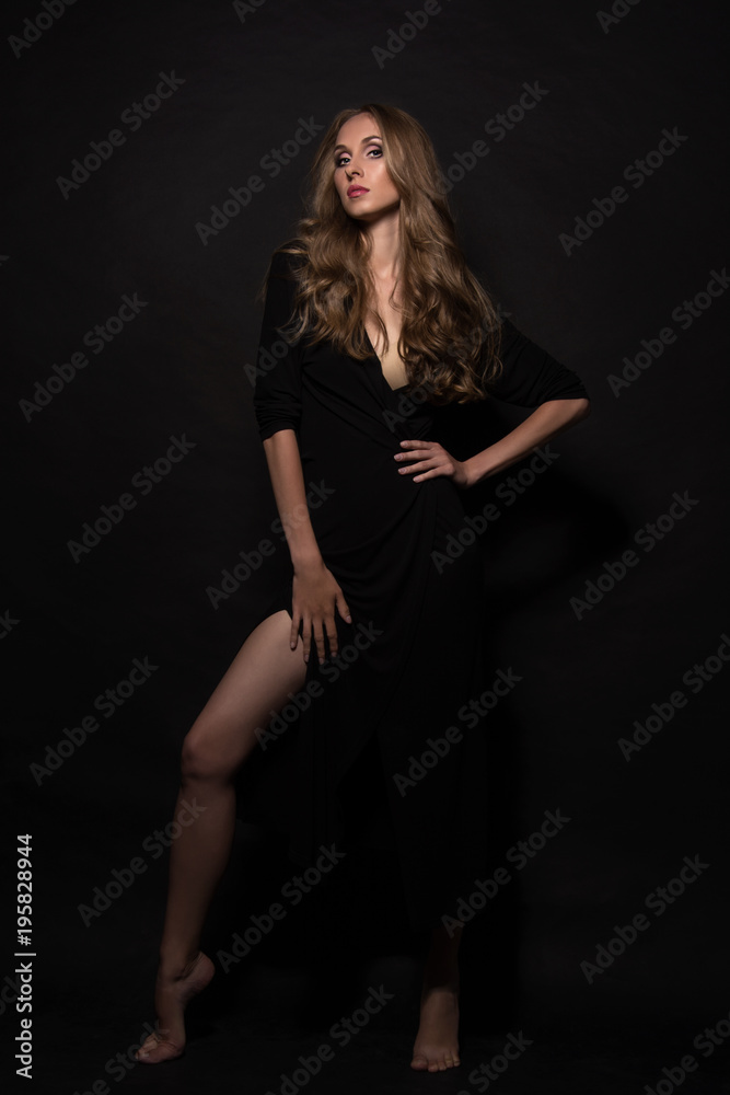 Portrait of a beautiful young sexy girl with long blond hair and evening make-up on a black background. Portrait of a beautiful young sexy girl with long blond hair and evening make-up on a black background.