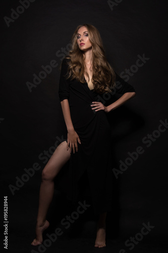Portrait of a beautiful young sexy girl with long blond hair and evening make-up on a black background.