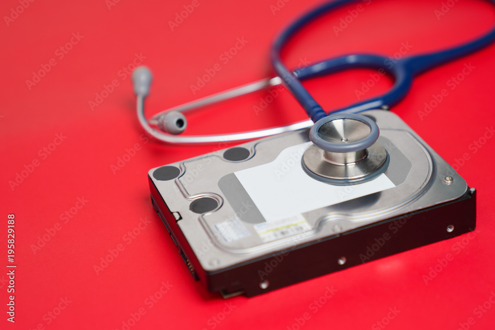 Stethoscope and hard disk drive on red background. Computer hardware diagnostic and repair concept Stethoscope and hard disk drive on red background. Computer hardware diagnostic and repair concept