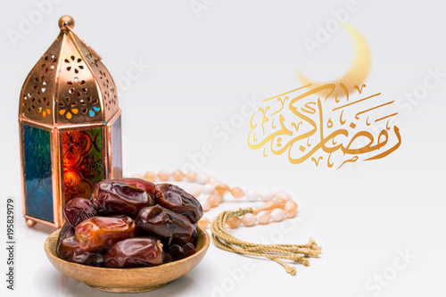 Ramadan Kareem Festive, close up of oriental Lantern lamp with dates on wooden plate and rosary on white background. Islamic Holy Month Greeting Card