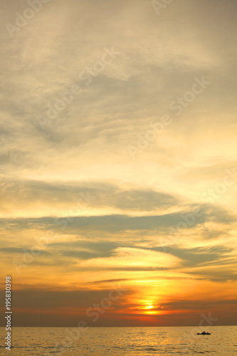 dramatic colorful sea sunset with sun setting on water lonely boat on horison