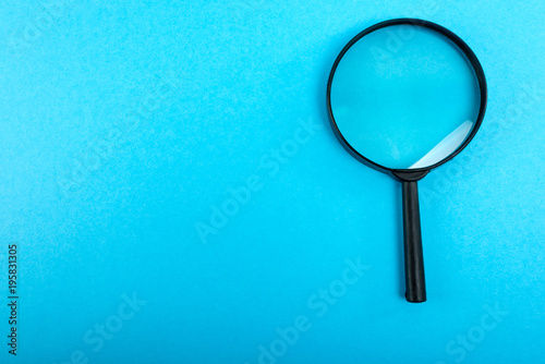 Magnifying glass on blue table. Top view.