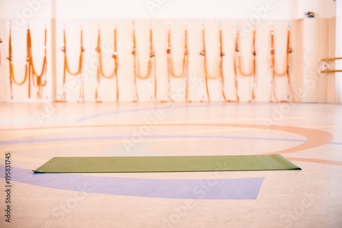 Empty space in fitness center, brick wall, natural wooden floor, modern loft studio, unrolled yoga mat on the floor.