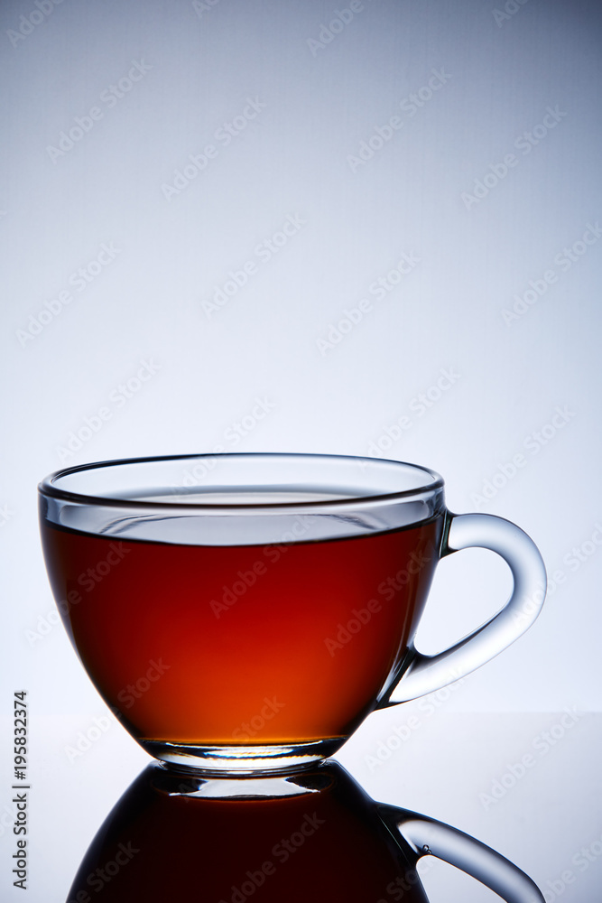 Glass transparent empty teacup on a light grey background, close-up, vertical. Glass transparent empty teacup on a light grey background, close-up, vertical.