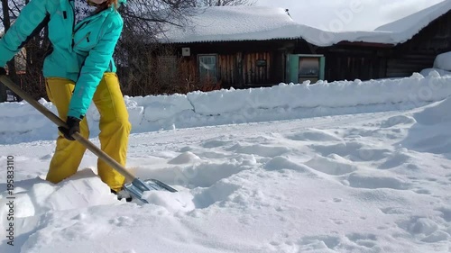 girl is clearing snow with shovel