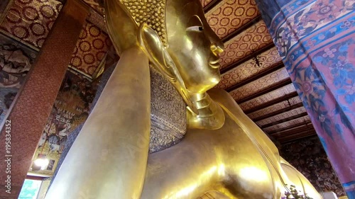 Reclining Buddha gold statue face in Wat Phra Chetupon Vimolmangklararm (Wat Pho) temple in Thailand photo