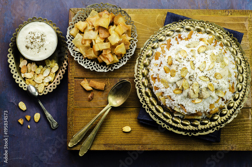 Arabic cuisine; Jordanian Chicken Mansaf of white rice and crispy fried bread topped with chunks of chicken,toasted almond and garlic yogurt sauce on copper plate.Top view photo