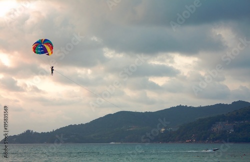 Towing boat pulls out a parachute with a tourist and an instructor, cloudy evening sky