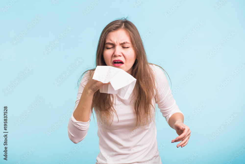 Young woman has a runny nose on blue background Young woman has a runny nose on blue background
