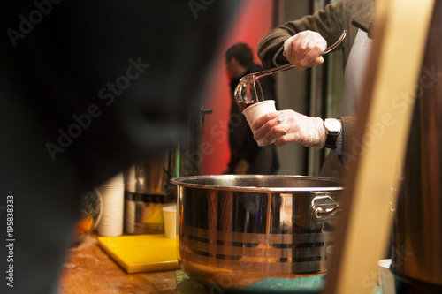 mulled wine and punch are poured into a glass from a large saucepan