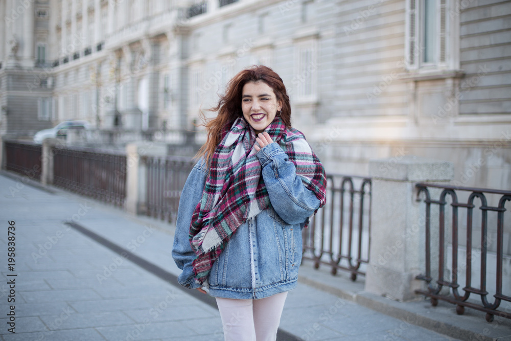 Attractive young girl in denim jacket and laughing on the street. 