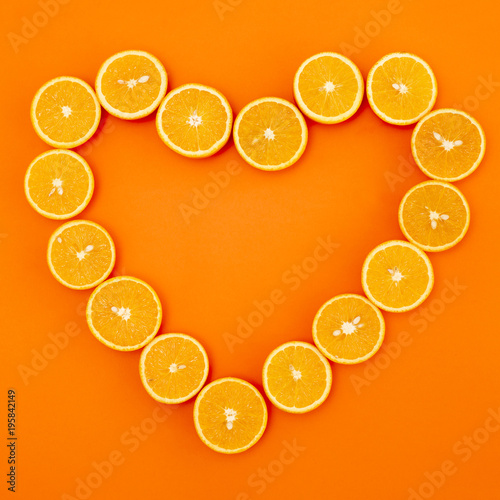 oranges cut in half are laid out in the shape of a heart on orange background