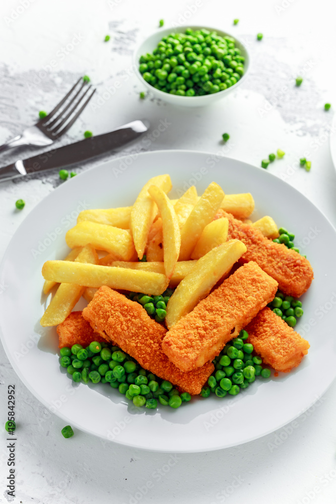 British Traditional Fish finger and chips with peas and tartar sauce in a white plate. British Traditional Fish finger and chips with peas and tartar sauce in a white plate.