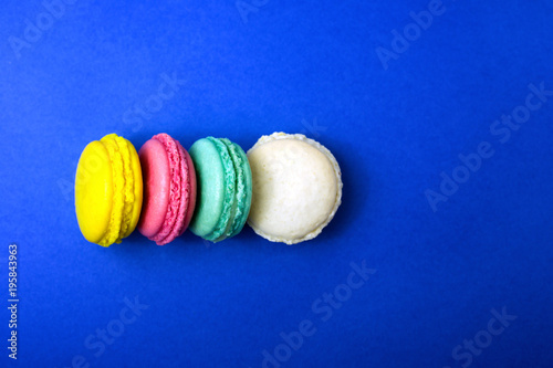 Colored macaroons on a blue background. Flat lay style. Place for your text.