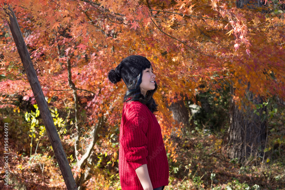 Young female posing in front of beautiful trees in Autumn when the leaves are red, orange and yellow Young female posing in front of beautiful trees in Autumn when the leaves are red, orange and yellow