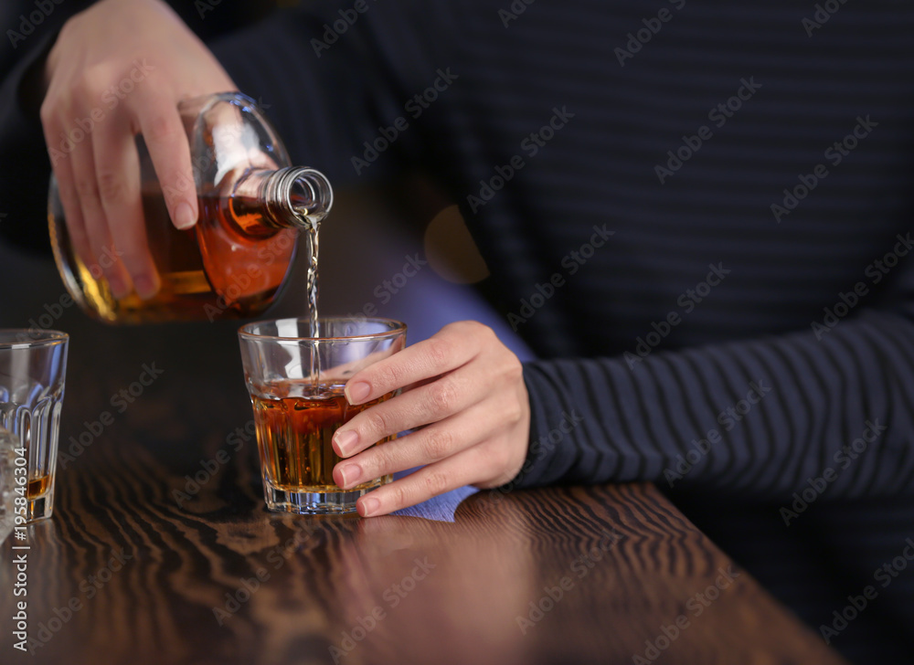 Woman pouring alcohol into drink at bar, closeup. Alcoholism problem Woman pouring alcohol into drink at bar, closeup. Alcoholism problem