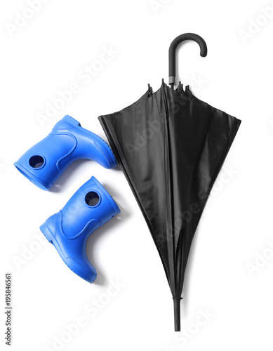 Black umbrella and gumboots on white background