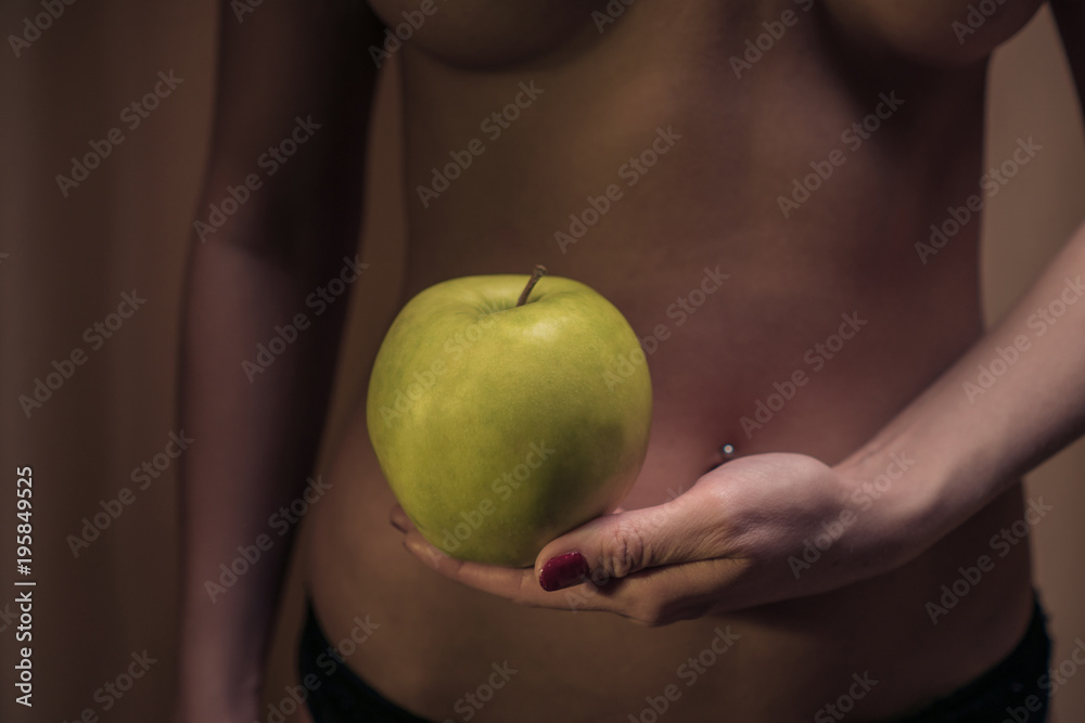 The concept of diet. Sexy female waist and an apple against the background of a woman's body. Healthy lifestyle The concept of diet. Sexy female waist and an apple against the background of a woman's body. Healthy lifestyle
