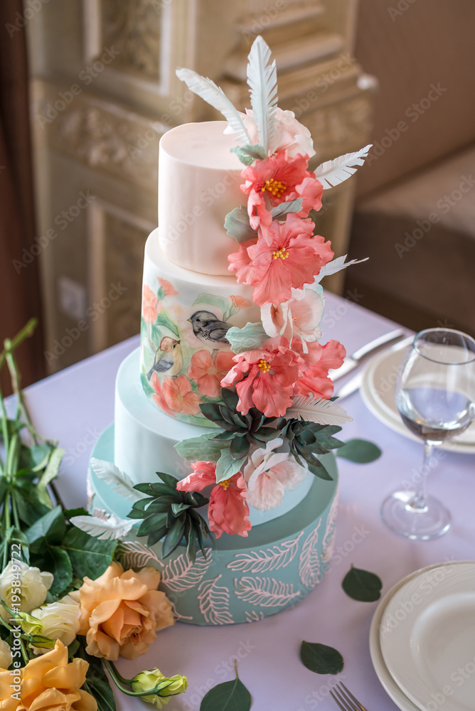 Home wedding for-tiered cake on the table in the restaurant decorated with pink roses and green leaves in a rustic style Home wedding for-tiered cake on the table in the restaurant decorated with pink roses and green leaves in a rustic style