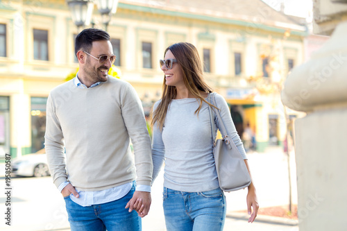 Beautiful young couple smiling while walking outdoors on sunny day