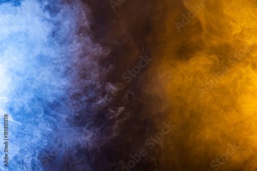 Blue and yellow smoke on a dark background. Texture and desktop picture
