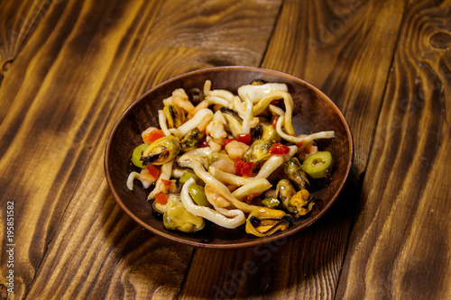 Seafood salad with shrimp, squid and mussels on wooden table