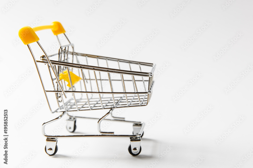 Close up of supermarket grocery push cart for shopping with black wheels and yellow plastic elements on handle isolated on white background. Concept of shopping. Copy space for advertisement Close up of supermarket grocery push cart for shopping with black wheels and yellow plastic elements on handle isolated on white background. Concept of shopping. Copy space for advertisement