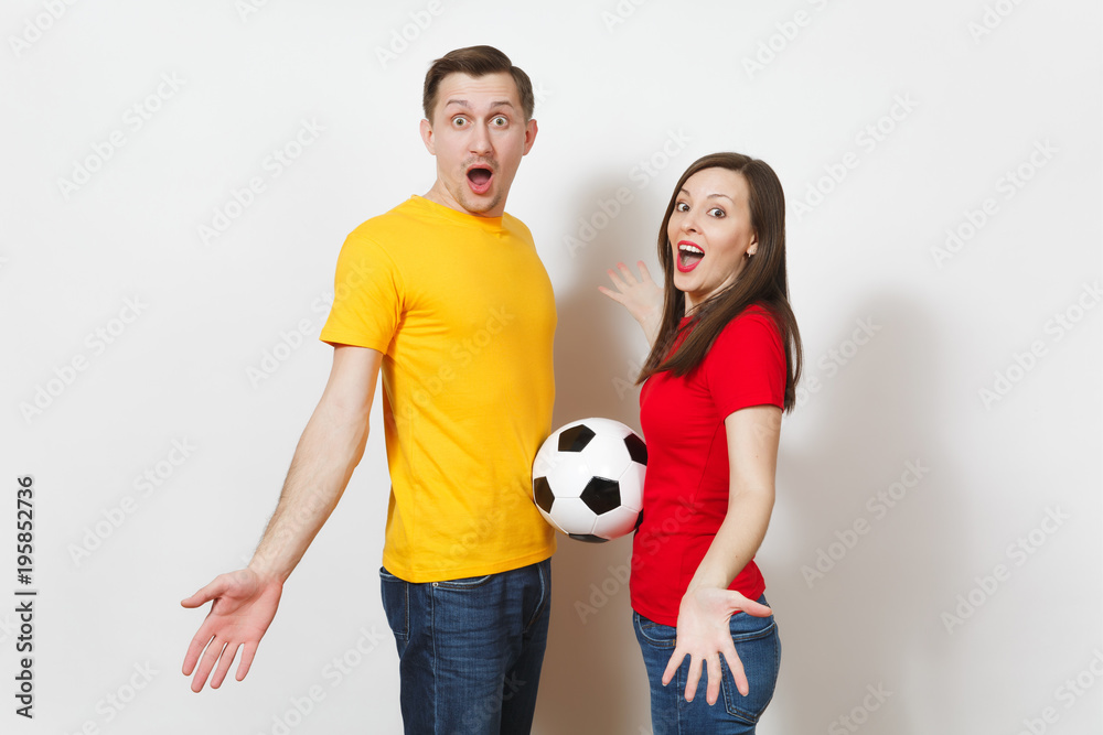 Fun smiling cheerful young couple, woman, man, football fans in yellow and red uniform cheer up support team holding soccer ball isolated on white background. Sport, family leisure, lifestyle concept. Fun smiling cheerful young couple, woman, man, football fans in yellow and red uniform cheer up support team holding soccer ball isolated on white background. Sport, family leisure, lifestyle concept.