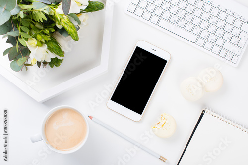 Lady bloggers work desk with fresh bouquet of flowers and macaro photo