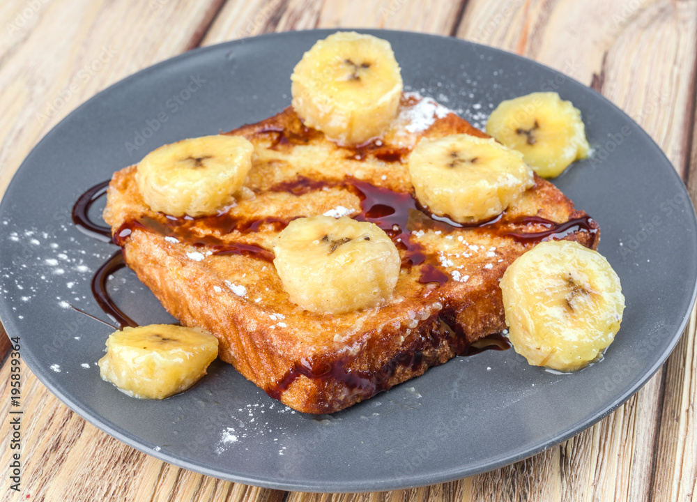 French toast with fried banana and syrup in natural wood