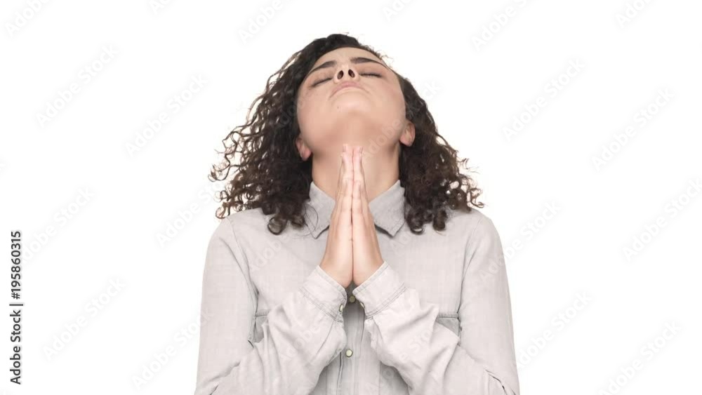 Portrait of serious young woman holding hands together, and asking god for good luck, over white background. Concept of emotions Portrait of serious young woman holding hands together, and asking god for good luck, over white background. Concept of emotions