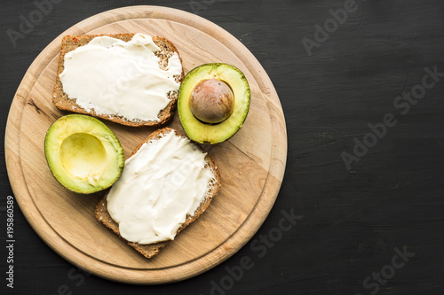 cut avocado and bread and butter on dark background. food photo. concept of proper nutrition, weight loss, overweight