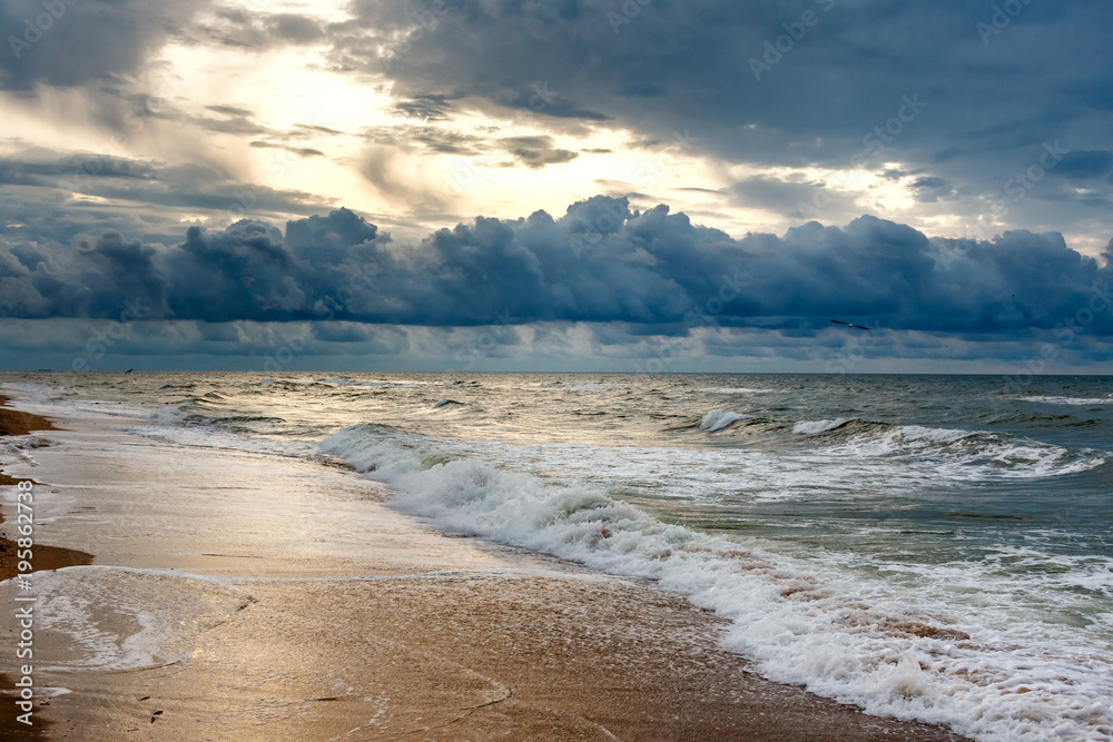 Dramatic sky on a morning seascape. Sunrise on a sandy beach.
