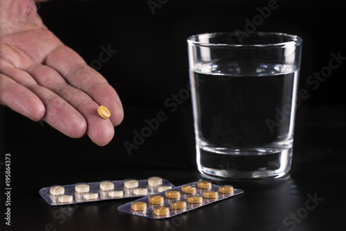 Man teenager hands with pills and glass of water.Dark tone.