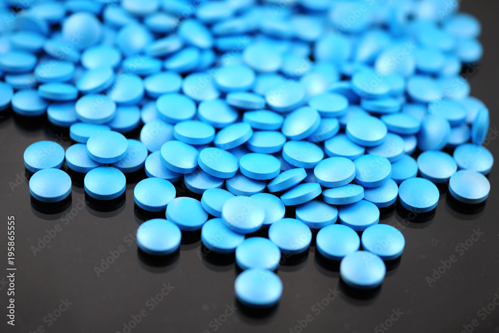 Bright blue round tablets closeup on black background Bright blue round tablets closeup on black background